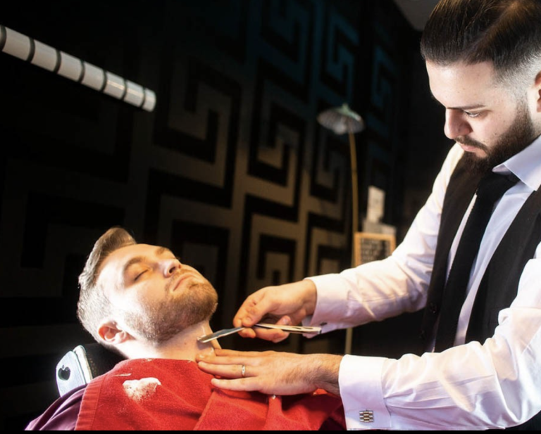 Barber using a straight razor along a client’s facial hair line